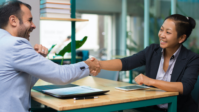 Two people shaking hands in an interview